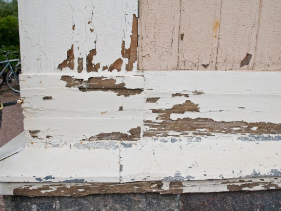 Assess the condition of paint on a wooden house