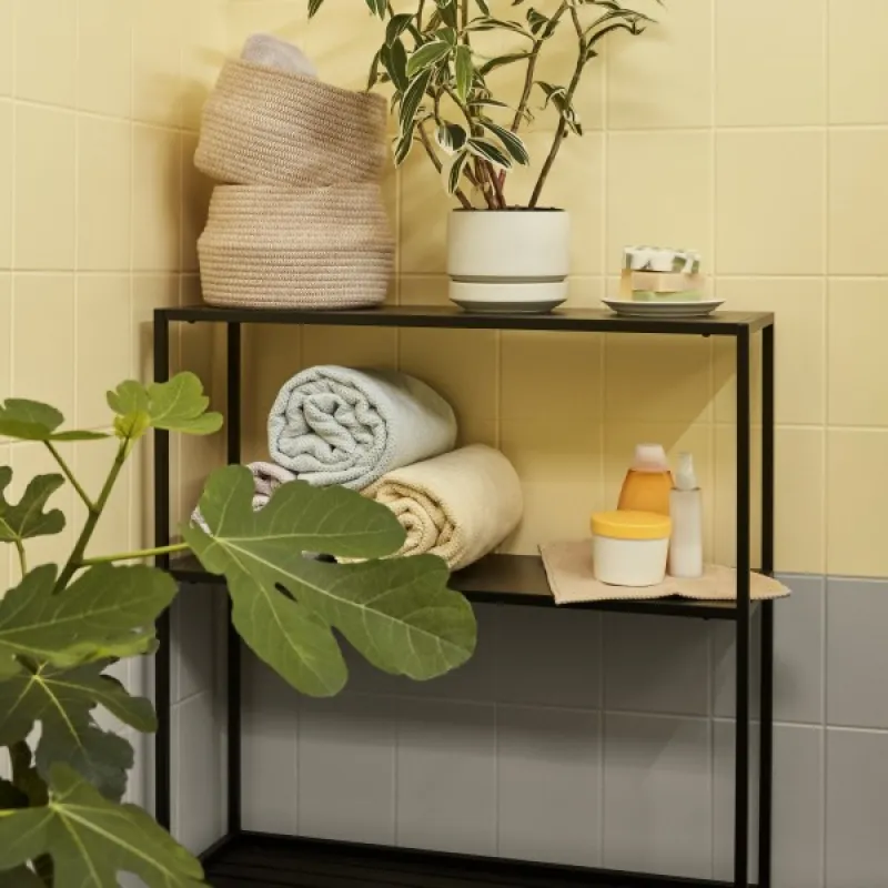 black shelf in front of yellow bathroom tile wall